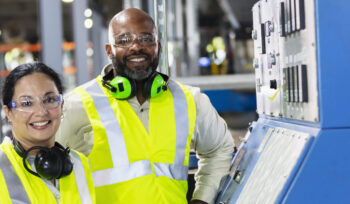 two manufacturing workers next to machine