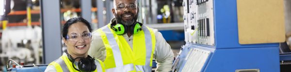 two manufacturing workers next to machine