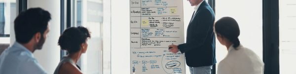 Business boss, meeting and whiteboard presentation of notes in workshop, schedule and team coaching. Manager writing ideas for training, seminar and strategy of charts, agenda and brainstorming data